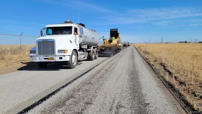 Paving of a rural road in Hermiston, Oregon with construction vehicles and workers visible.